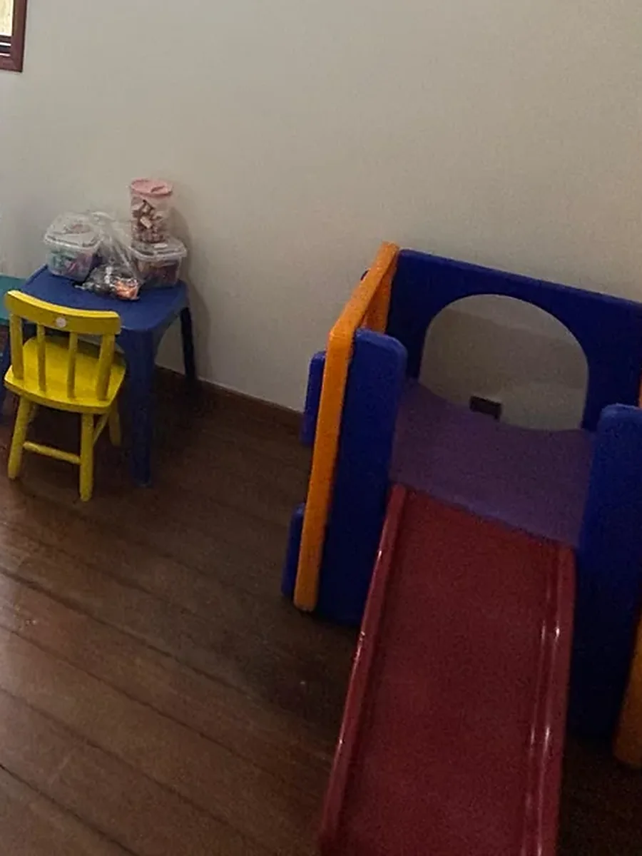 Canto de brincar da sala de atendimento infantil do Instituto Fonnare, com mesa, cadeiras e escorregador